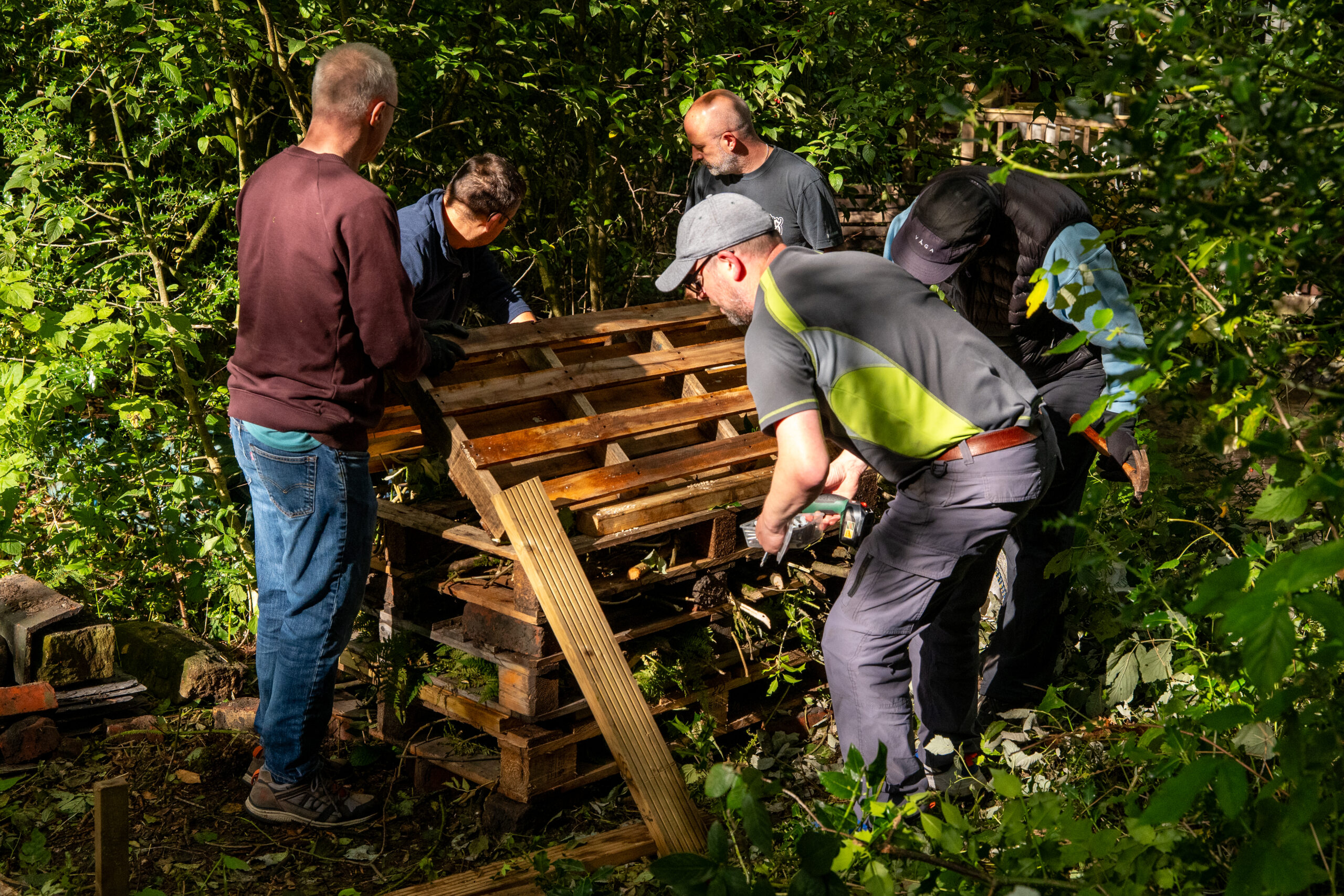 Four men working on a bug hotel construction