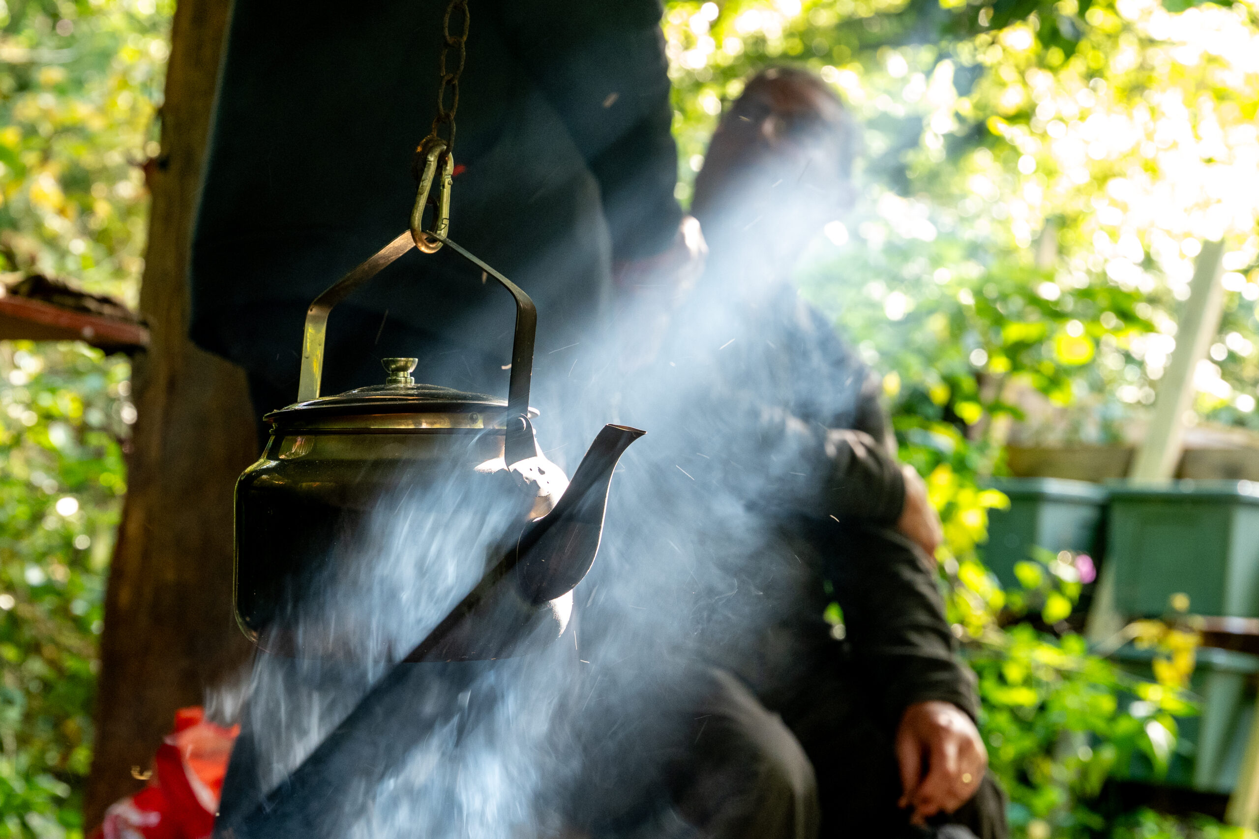 Silver kettle over a smoky fire pit
