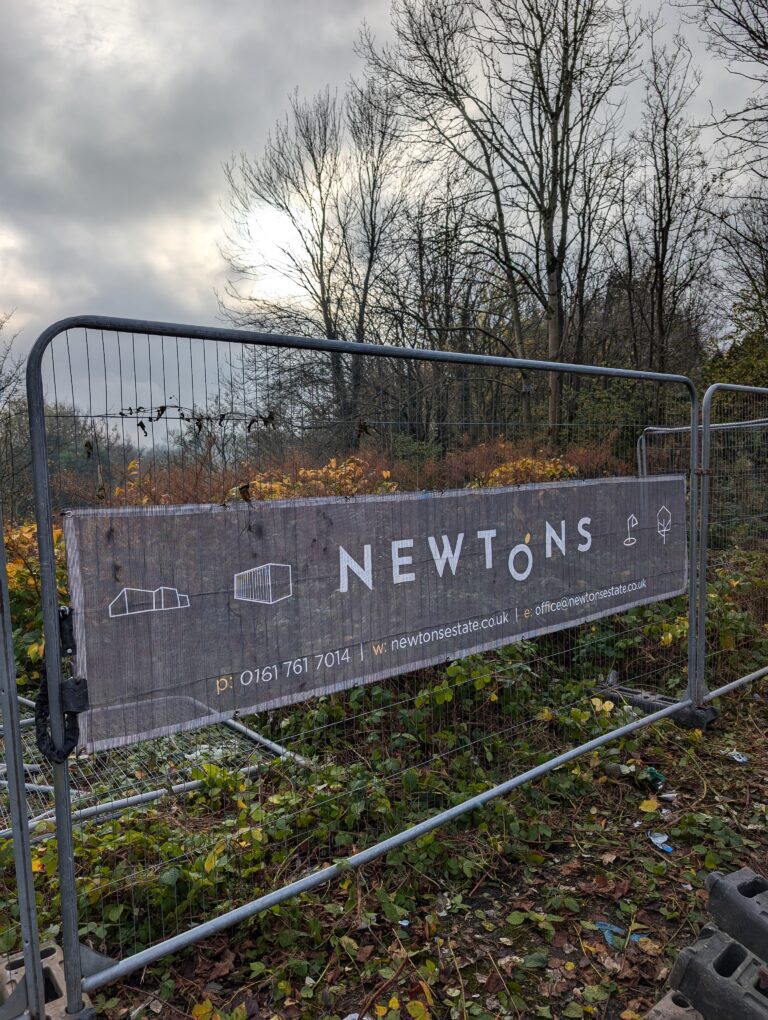 A black Newtons banner on metal construction fencing